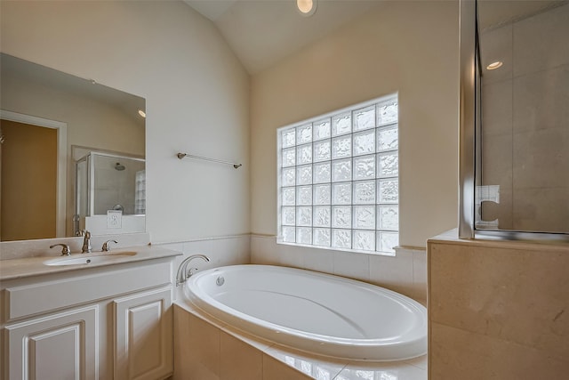 bathroom with a garden tub, a shower stall, vaulted ceiling, and vanity