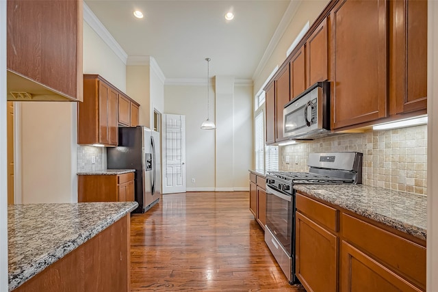 5938 Kansas St, Houston, TX 77007 - kitchen with stainless steel appliances, ornamental molding, brown cabinetry, dark stone countertops, and recessed lighting