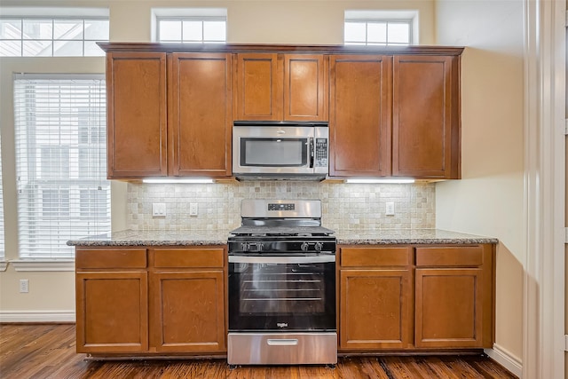 5938 Kansas St, Houston, TX 77007 - kitchen featuring appliances with stainless steel finishes, dark wood-style flooring, backsplash, and light stone counters