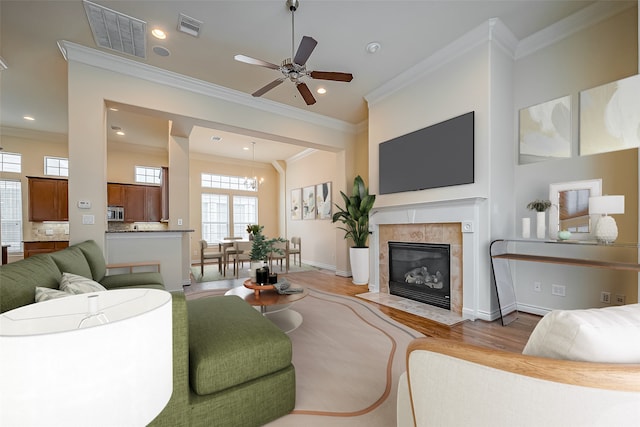 living room featuring visible vents, a ceiling fan, wood finished floors, and ornamental molding