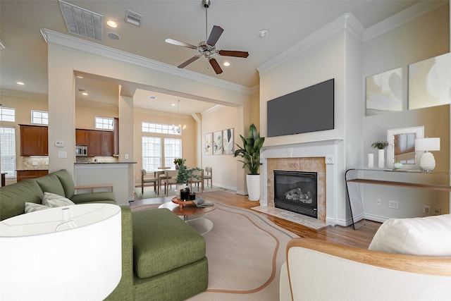 living room with ornamental molding, wood finished floors, visible vents, and baseboards