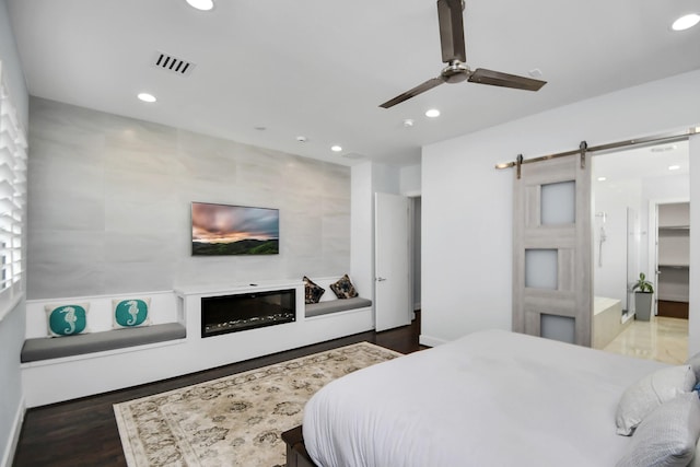 bedroom featuring a barn door, wood finished floors, recessed lighting, and visible vents