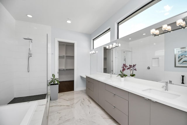 bathroom with double vanity, tiled shower, an inviting chandelier, and a sink