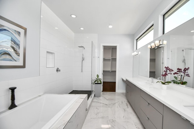 bathroom with a garden tub, double vanity, a stall shower, and a sink