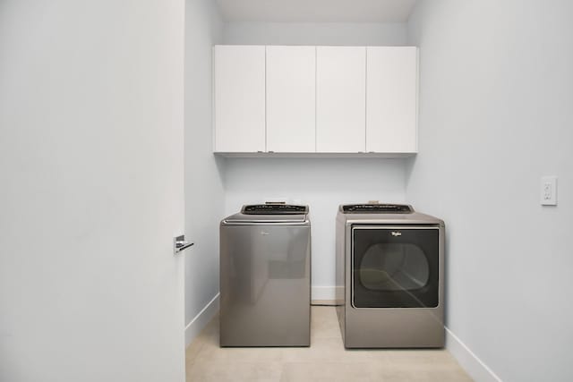 washroom featuring baseboards, cabinet space, and washer and clothes dryer