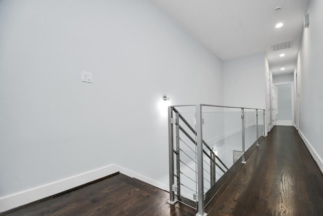 corridor featuring dark wood-style floors, visible vents, baseboards, recessed lighting, and an upstairs landing