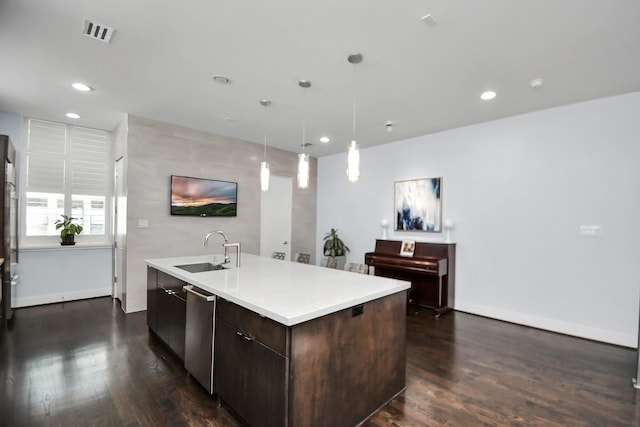 kitchen featuring visible vents, an island with sink, a sink, dark wood-type flooring, and dark brown cabinets