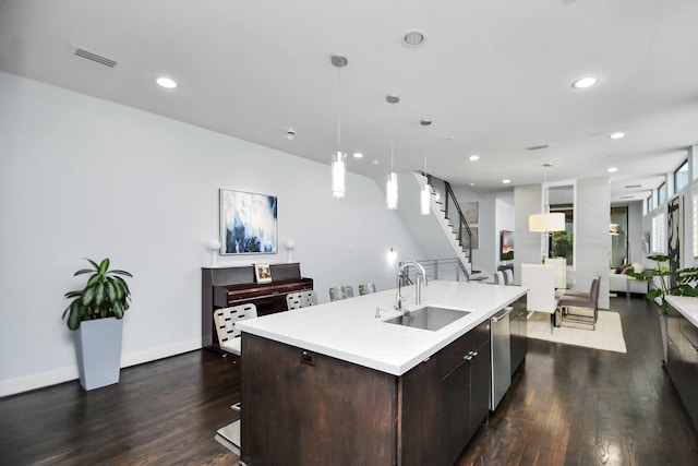 kitchen featuring visible vents, dark wood-type flooring, dark brown cabinetry, an island with sink, and a sink