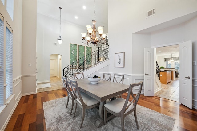 dining space with visible vents, stairway, arched walkways, an inviting chandelier, and light wood finished floors