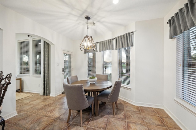 dining space with baseboards, arched walkways, visible vents, and a chandelier