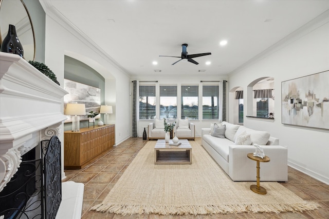 tiled living room with a fireplace with raised hearth, crown molding, recessed lighting, arched walkways, and a ceiling fan