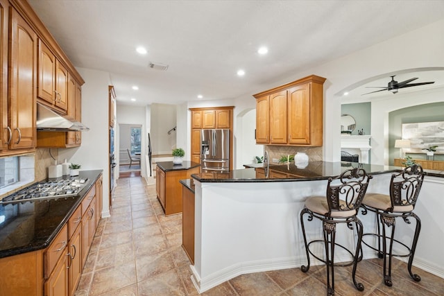 kitchen with visible vents, ceiling fan, under cabinet range hood, a peninsula, and stainless steel appliances