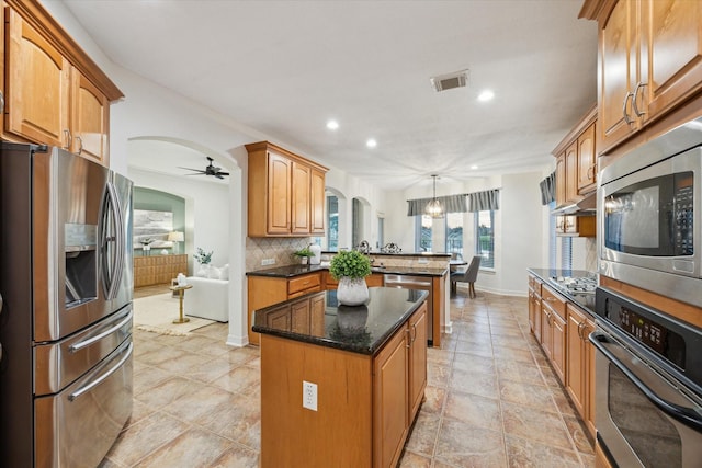 kitchen featuring visible vents, a kitchen island, decorative backsplash, appliances with stainless steel finishes, and a peninsula