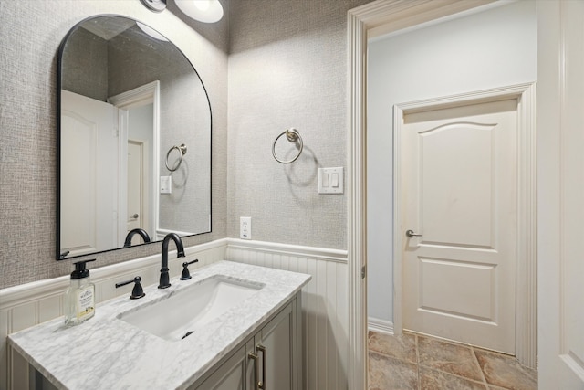 bathroom with a wainscoted wall, vanity, and wallpapered walls