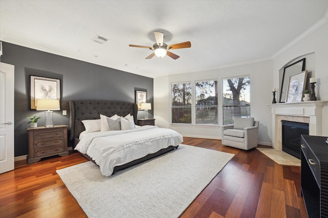 bedroom featuring baseboards, dark wood-style floors, crown molding, and a tiled fireplace