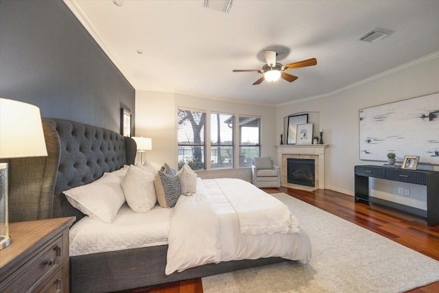 bedroom featuring visible vents, a fireplace, crown molding, and wood finished floors