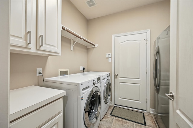 clothes washing area with washer and clothes dryer, visible vents, and cabinet space