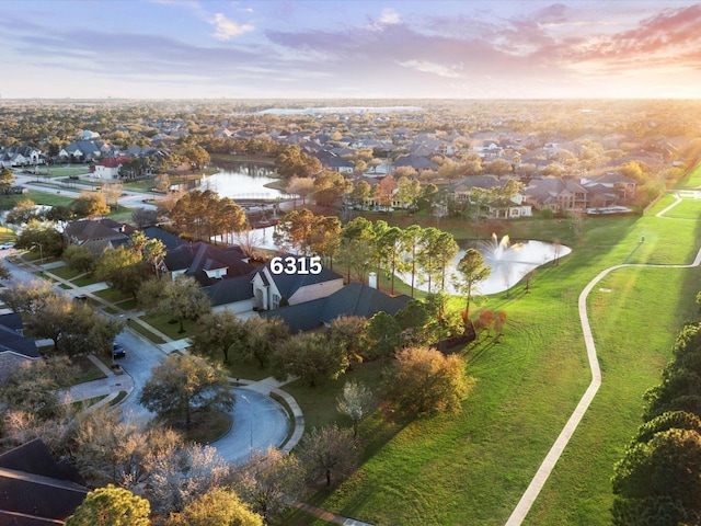 aerial view at dusk featuring a residential view and a water view