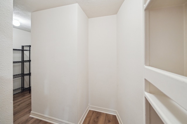 interior space with baseboards, a textured ceiling, and wood finished floors