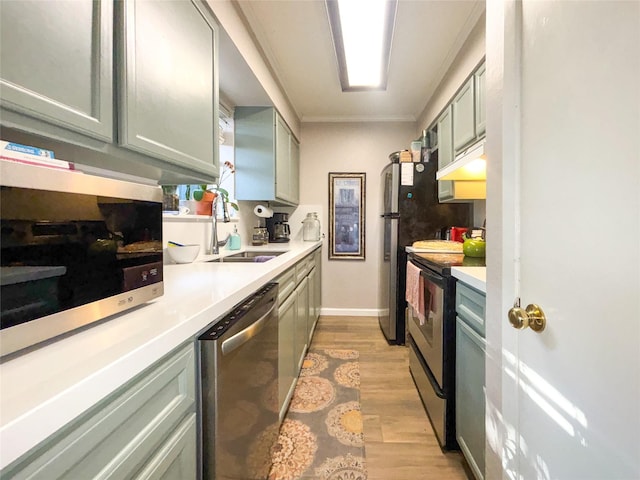 kitchen with stainless steel appliances, light countertops, a sink, and light wood finished floors