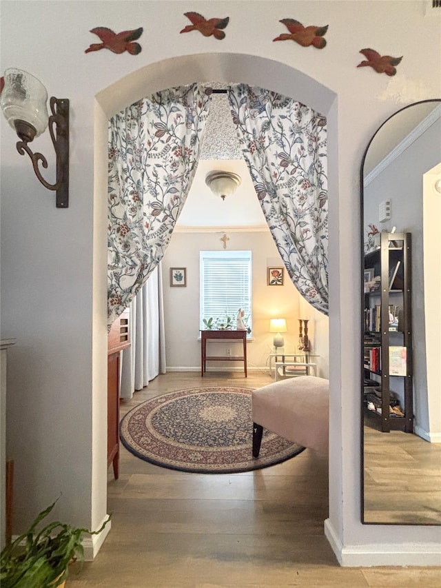 hall with crown molding, baseboards, and wood finished floors