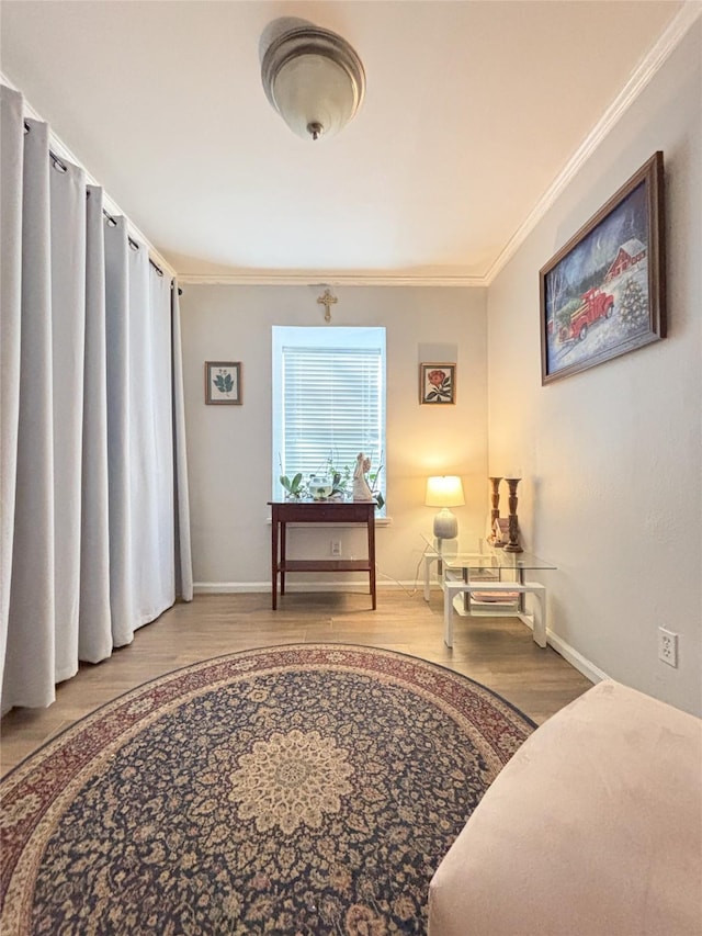 living area featuring baseboards, crown molding, and wood finished floors