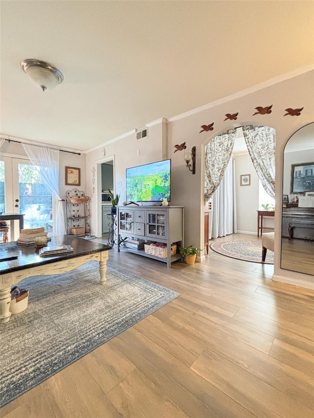 living room featuring visible vents, arched walkways, wood finished floors, and ornamental molding