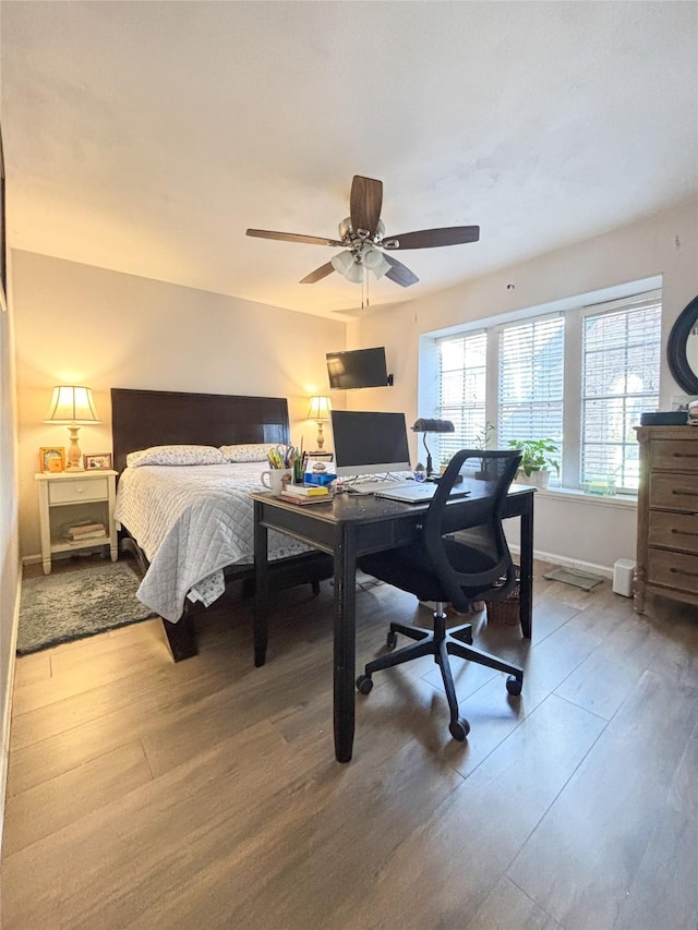 bedroom with ceiling fan, baseboards, and wood finished floors