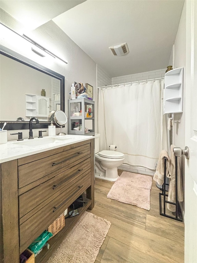 full bath featuring toilet, a shower with shower curtain, wood finished floors, visible vents, and vanity