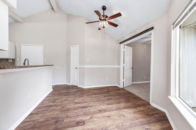 spare room with lofted ceiling with beams, baseboards, dark wood finished floors, and a ceiling fan