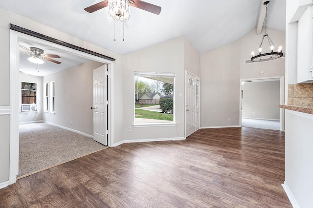 interior space with vaulted ceiling with beams, ceiling fan with notable chandelier, wood finished floors, and baseboards