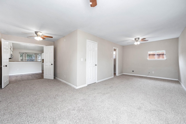 empty room with carpet floors, attic access, a ceiling fan, and baseboards