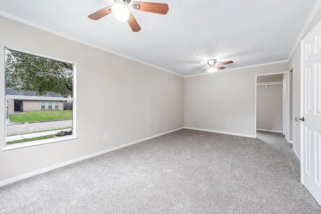 empty room with ornamental molding, carpet flooring, a ceiling fan, and baseboards