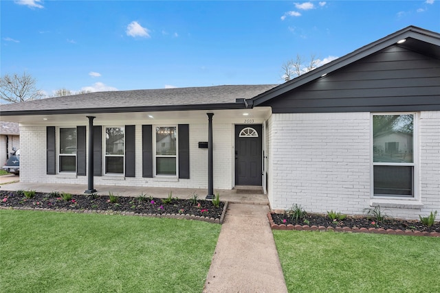 single story home featuring a front lawn, a porch, brick siding, and a shingled roof