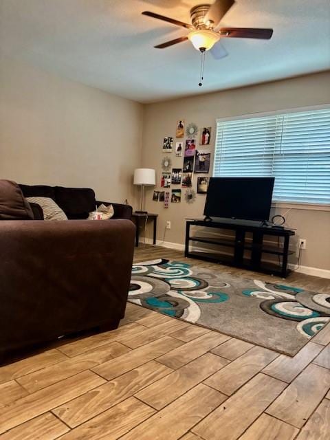 living room with light wood-style floors, ceiling fan, and baseboards