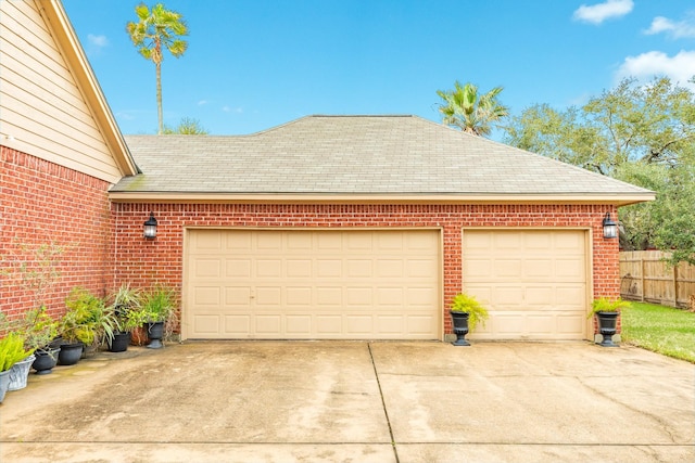 garage featuring driveway and fence