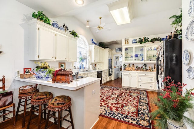 kitchen with dark wood finished floors, lofted ceiling, light countertops, ceiling fan, and a peninsula