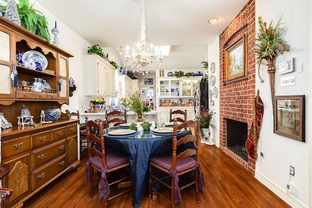 dining room with a brick fireplace, baseboards, dark wood finished floors, and an inviting chandelier