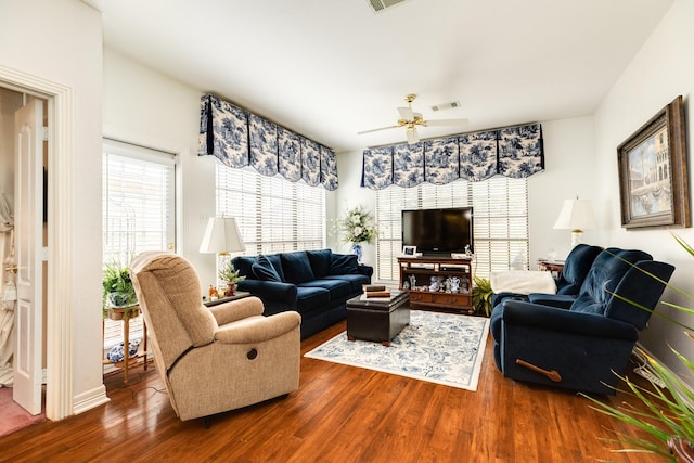 living room with dark wood-type flooring, visible vents, and ceiling fan