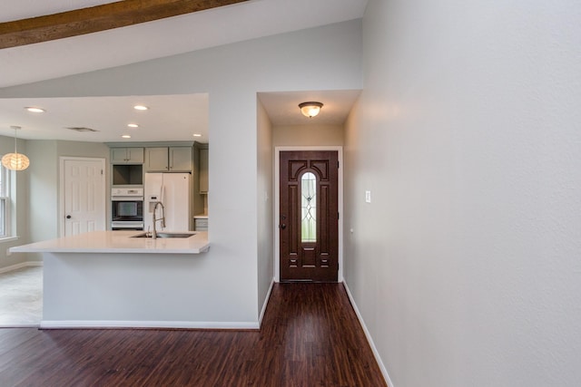 interior space with lofted ceiling, white refrigerator with ice dispenser, wood finished floors, a sink, and baseboards