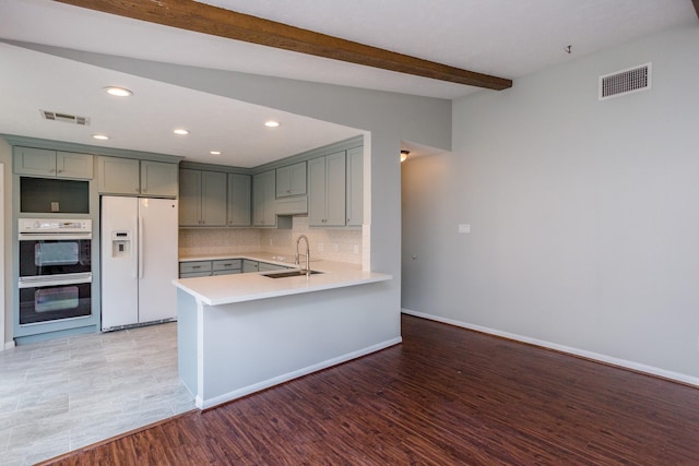 kitchen featuring white fridge with ice dispenser, gray cabinets, visible vents, and decorative backsplash