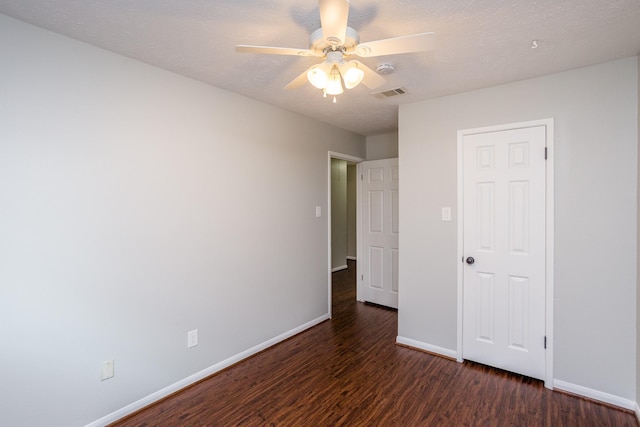 unfurnished bedroom featuring a textured ceiling, dark wood finished floors, visible vents, and baseboards