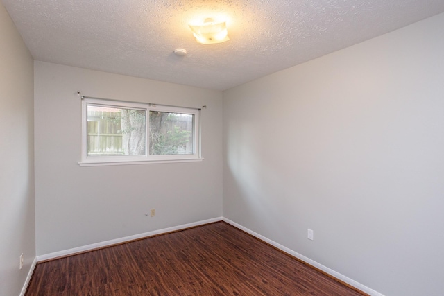 unfurnished room with a textured ceiling, baseboards, and wood finished floors