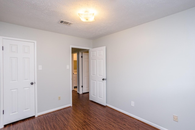 unfurnished bedroom with visible vents, a textured ceiling, baseboards, and wood finished floors