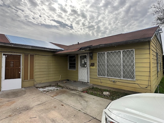 view of front facade featuring roof with shingles and a patio