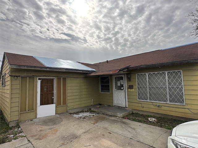 exterior space featuring a patio and roof with shingles