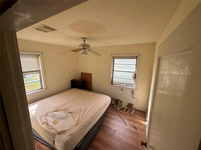 bedroom featuring wood finished floors, visible vents, ceiling fan, and multiple windows