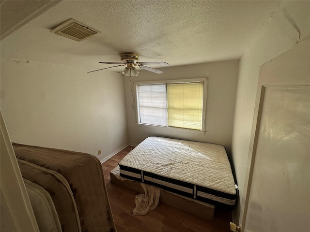 bedroom with visible vents, ceiling fan, a textured ceiling, wood finished floors, and baseboards