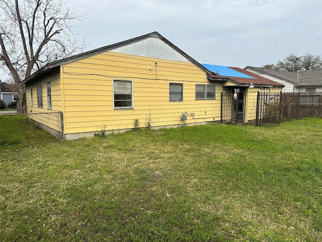 rear view of property featuring a lawn and fence