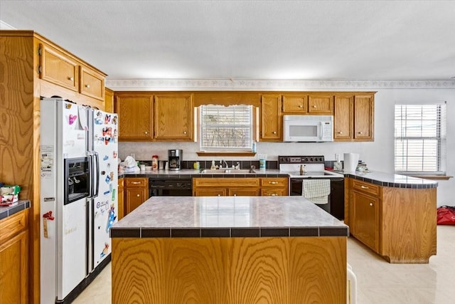 kitchen with white appliances, brown cabinets, a sink, and a peninsula